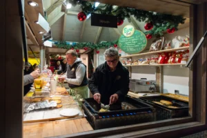 Frische Zubereitung von Speisen auf dem Grill eines Weihnachtsmarktstands.