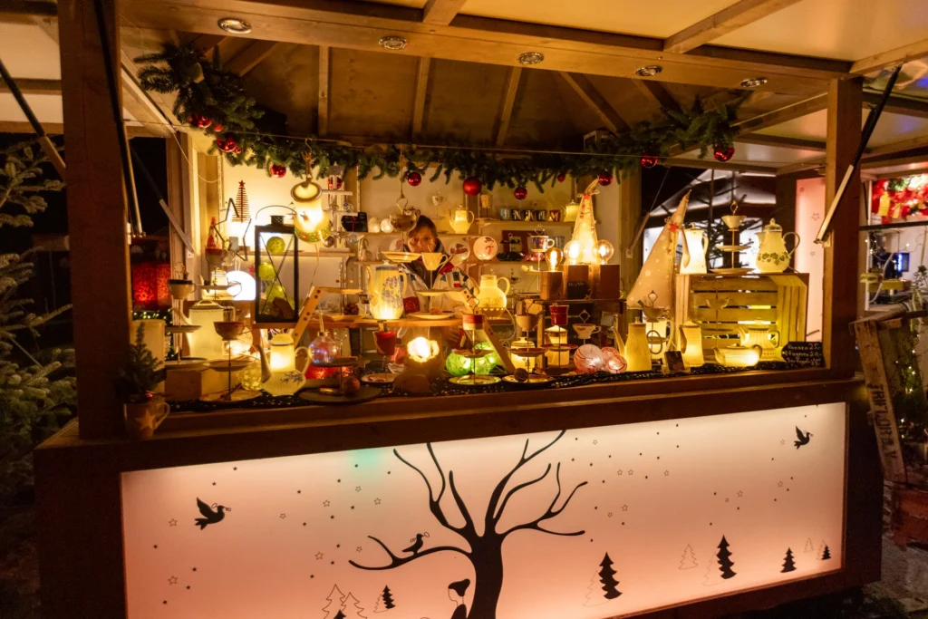 Kunsthandwerksstand auf dem Weihnachtsmarkt Beleuchteter Weihnachtsmarktstand mit handgefertigten Dekorationsartikeln.